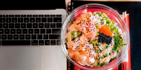 A poke bowl next to a laptop